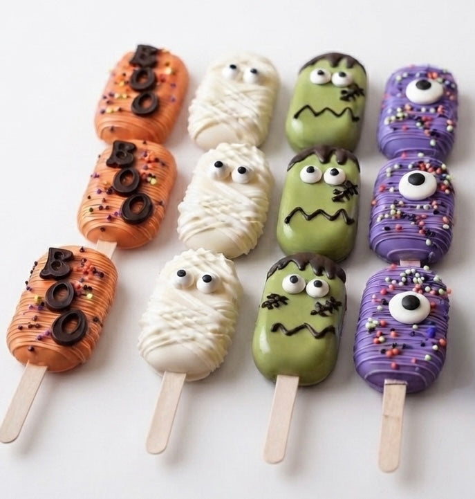 12 handmade Halloween Monster Cakesicles decorated with colorful monster faces and chocolate coating.
Halloween Monster Cakesicles box with 12 individually wrapped chocolate-covered cake pops for parties and gifts.
Cute Halloween monster cakesicles featuring spooky monster designs, candy decorations, and festive colors.
Handcrafted Halloween cakesicles with monster faces, perfect for Halloween parties, dessert tables, and party favors.
A dozen Halloween Monster Cakesicles made with cake filling, premium cho